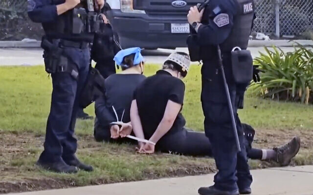 Des manifestants pro-palestiniens détenus avant d'être arrêtés par des officiers de police de Los Angeles, près de l'aéroport international de Los Angeles, le 27 décembre 2023. (Crédit : KABC-TV via AP)