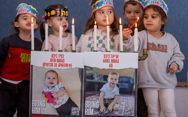 Des photographies de Kfir et Ariel Bibas, retenus en otage par les terroristes du Hamas, sur une menorah allumée par des enfants dans une crèche du Moshav Yashresh, dans le centre d'Israël, pendant Hanoukka, le 12 décembre 2023. (Crédit : Yossi Aloni/Flash90) Des photographies de Kfir et Ariel Bibas, retenus en otage par les terroristes du Hamas, sur une menorah allumée par des enfants dans une crèche du Moshav Yashresh, dans le centre d'Israël, pendant Hanoukka, le 12 décembre 2023. (Crédit : Yossi Aloni/Flash90)