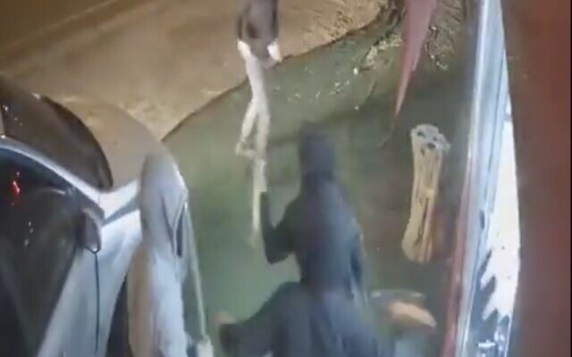 Des résidents d’implantations filmés en train de détruire la devanture d'un magasin dans le village palestinien d'As-Sawiya, le 1er décembre 2023. (Crédit : Capture d'écran/X)