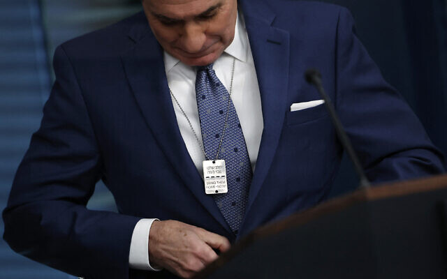 John Kirby porte un collier avec une plaque 'Bring Them Home-Now'  réclamant la libération des otages en hébreu et en anglais lors d'un point-presse à la Maison Blanche, à Washington, le 13 décembre 2023. (Crédit : Chip Somodevilla/Getty Images/AFP)