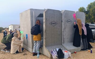 Des bénévoles bédouins peignant un abri anti-aérien en béton installé dans le village bédouin non-reconnu d'Umm al-Khiran, dans le sud d'Israël, le 7 décembre 2023. (Crédit : Gianluca Pacchiani/Times of Israel)