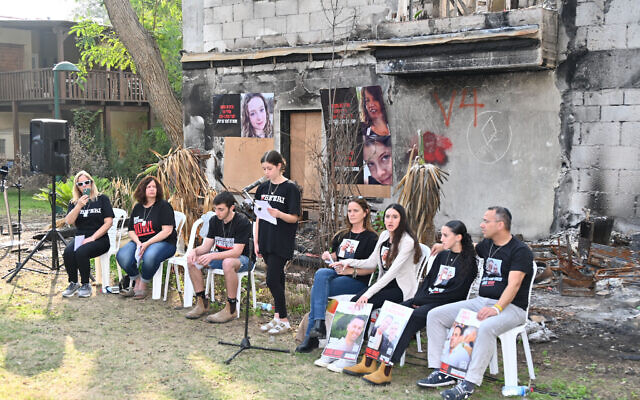 D'anciens otages et des survivants de l'invasion et du massacre perpétrés par le groupe terroriste palestinien du Hamas le 7 octobre 2023 s'adressant aux journalistes devant les décombres calcinés de la maison de Raaya et Hila Rotem, au kibboutz Beeri, le 1ᵉʳ janvier 2024. (Crédit : Canaan Lidor/Times of Israel)
