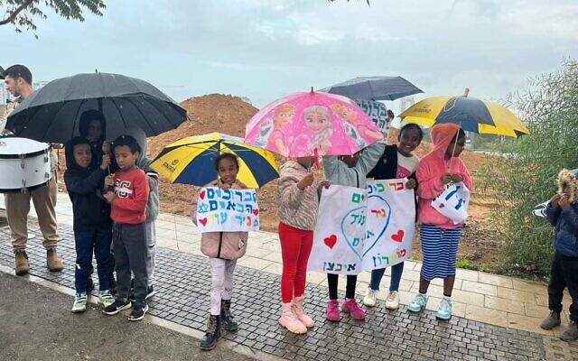 Des écoliers brandissent des pancartes où il est écrit "Bienvenue Nir Oz" à Kiryat Gat le 2 janvier 2024. (Crédit : Auhorisation/Municipalité de Kiryat Gat)