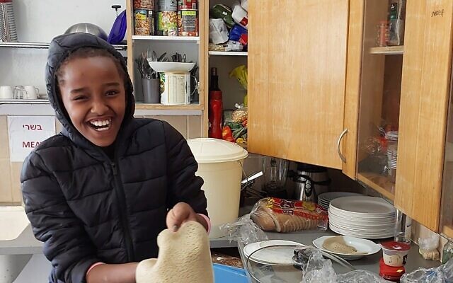Bena Hagdu, neuf ans, tient du pain injera au Centre éducatif Hannaton du kibboutz Hanaton, en décembre 2023. (Crédit : Omer Sharvit/ Zman)