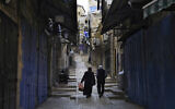 Des Palestiniens passant devant des boutiques fermées dans la Vieille Ville de Jérusalem, le 16 octobre 2023. (Crédit : Jon Gambrell/AP)