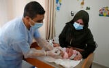 Un employé de l'UNRWA vaccinant un bébé contre la polio et le virus Rota, dans un dispensaire du camp de réfugiés de Bureij, dans le centre de la bande de Gaza, le 9 septembre 2020. (Crédit : Mohammed Abed/AFP)