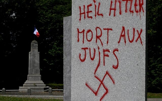 Illustration : Un graffiti en allemand et en français indiquant "Heil Hitler, mort aux Juifs" et avec une croix gammée, sur un monument à la mémoire de 55 personnes exécutées à cet endroit par les nazis en 1944 pendant la Seconde Guerre mondiale, à Ploeuc-L'Hermitage, dans l'ouest de la France, le 17 juillet 2023. (Crédit : Damien Meyer/AFP)