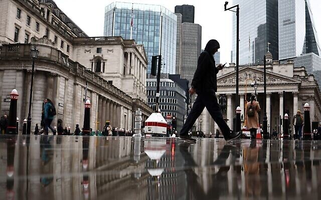 Des personnes passent devant le bâtiment de la Banque d'Angleterre (à gauche) et le bâtiment de la Bourse (à droite), dans le quartier financier au centre de Londres, le 2 novembre 2023. (Crédit : HENRY NICHOLLS / AFP) Des personnes passent devant le bâtiment de la Banque d'Angleterre (à gauche) et le bâtiment de la Bourse (à droite), dans le quartier financier au centre de Londres, le 2 novembre 2023. (Crédit : HENRY NICHOLLS / AFP)
