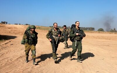 Des soldats de l’armée israélienne marchant près de la frontière avec la bande de Gaza en Israël à leur retour de Gaza, le 31 décembre 2023. (Crédit : Menahem Kahana/AFP)