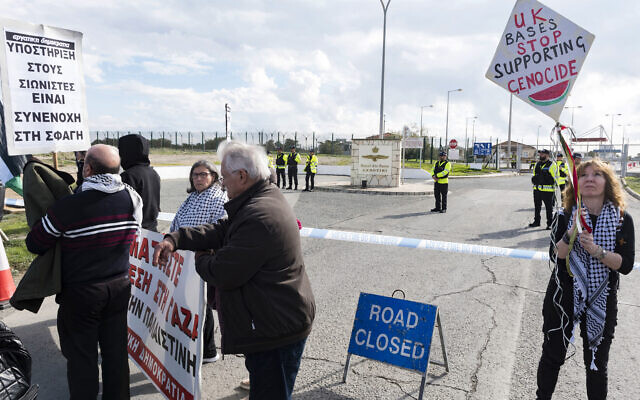 Des manifestants se rassemblent devant les portes de la base de la Royal Air Force à Akrotiri, un territoire britannique d'outre-mer près de la ville côtière chypriote de Limassol, alors qu'ils protestent contre son utilisation présumée pour approvisionner la guerre d'Israël à Gaza, une accusation démentie par la Grande-Bretagne, le 14 janvier 2024. (Crédit : Iakovos Hatzistavrou / AFP) Des manifestants se rassemblent devant les portes de la base de la Royal Air Force à Akrotiri, un territoire britannique d'outre-mer près de la ville côtière chypriote de Limassol, alors qu'ils protestent contre son utilisation présumée pour approvisionner la guerre d'Israël à Gaza, une accusation démentie par la Grande-Bretagne, le 14 janvier 2024. (Crédit : Iakovos Hatzistavrou / AFP)