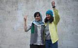 Cette photo, prise et diffusée par le site d'information Sharq News le 14 janvier 2024, montre les journalistes iraniennes Niloufar Hamedi (à droite) et Elaheh Mohammadi (à gauche) faisant le signe de la victoire après leur libération de la prison d'Evin sous caution à Téhéran. Les autorités iraniennes ont libéré deux journalistes qui ont passé plus d'un an derrière les barreaux pour avoir couvert la mort de Mahsa Amini, déclenchant des protestations nationales de plusieurs mois, selon les médias locaux. (Crédit : Sahand TAKI / Sharq news online / AFP)
