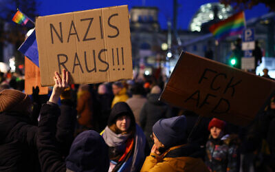 Un participant tient un écriteau indiquant « les nazis dehors » lors d'une manifestation contre le racisme et la politique d'extrême droite devant le bâtiment du Reichstag, à Berlin, le 21 janvier 2024. (Crédit : Christian Mang/AFP)