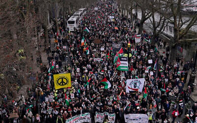 Des manifestants brandissant des bannières, des drapeaux et des pancartes alors qu'ils marchent le long de l'Embankment au bord de la Tamise lors d'une manifestation anti-Israël, à Londres, le 13 janvier 2024. (Crédit : Alberto Pezzali/AP)