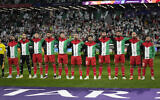 L'équipe palestinienne écoute son hymne avant le match de football du Groupe C de la Coupe d'Asie entre l'Iran et la Palestine au stade Education City à Al-Rayyan, au Qatar, le 14 janvier 2024. (Crédit : AP/Aijaz Rahi)