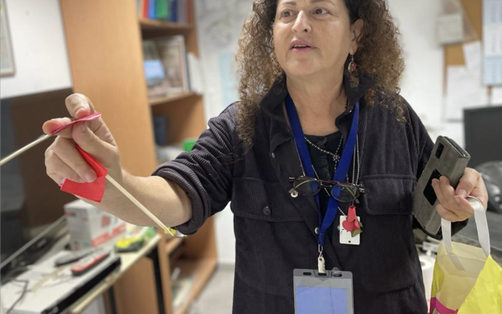 Nirit Shalev-Khalifa plaçant un petit drapeau rouge à côté des objets qu'elle veut récupérer, dans ce cas de la cellule de crise de l'équipe de sécurité du kibboutz Kfar Aza, près de la frontière de Gaza, le 2 janvier 2024. (Crédit : Sue Surkes/Times of Israel)