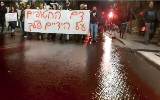 Des manifestants versent de l'eau teintée en rouge, représentant du sang, sur la rue Azza à Jérusalem, le 22 janvier 2024. (Crédit : Capture d'écran/X)