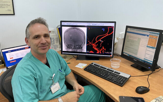 Le docteur Gal Yaniv,  chef de l'unité de chirurgie endovasculaire, à côté de son ordinateur à l'hôpital Sheba avec, sur l'écran, une notification de l'application Aidoc, le 28 décembre 2023.  (Crédit : Renee Ghert-Zand/Times of Israel)