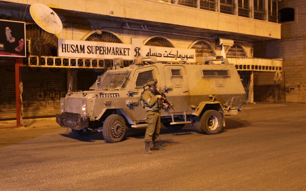 Un soldat de l’armée israélienne se tenant prêt devant un véhicule blindé lors d'une opération dans la ville de Hébron, en Cisjordanie, le 17 juin 2014. (Crédit : Hazem BaderAFP) 