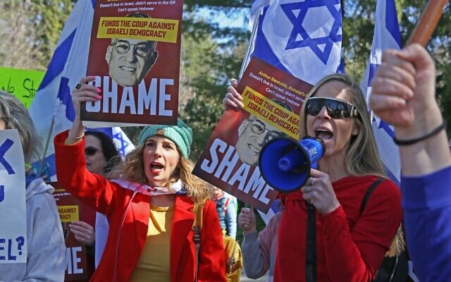 Des manifestants contre Kohelet Policy Forum brandissant des panneaux critiquant Arthur Dantchik près de la maison de ce dernier, dans les faubourgs de Philadelphie, le 26 mars 2023. (Crédit : Roy Boshi)