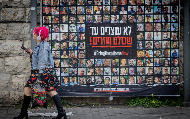 Des personnes marchent à côté de photos de civils pris en otage par des terroristes du Hamas à Gaza, à Jérusalem, le 12 février 2024. (Crédit : Chaim Goldberg/Flash90)
