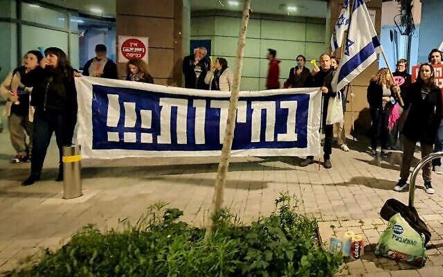 Dans une photo fournie par des militants anti-gouvernementaux, des manifestants tiennent une bannière appelant à des élections devant le domicile du ministre des Renseignements Gila Gamliel, à Tel Aviv, le 22 février 2024. (Crédit : Udi Salmanovich) Dans une photo fournie par des militants anti-gouvernementaux, des manifestants tiennent une bannière appelant à des élections devant le domicile du ministre des Renseignements Gila Gamliel, à Tel Aviv, le 22 février 2024. (Crédit : Udi Salmanovich)