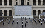 Le président français Emmanuel Macron marchant devant des membres de la Garde républicaine française tenant des portraits des 42 citoyens français et franco-israéliens tués, lors d'une cérémonie d'hommage aux victimes françaises du pogrom du Hamas contre Israël le 7 octobre, au complexe commémoratif des Invalides à Paris, le 7 février 2024. (Crédit : AFP)