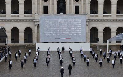 Le président français Emmanuel Macron marchant devant des membres de la Garde républicaine française tenant des portraits des 42 citoyens français et franco-israéliens tués, lors d'une cérémonie d'hommage aux victimes françaises du pogrom du Hamas contre Israël le 7 octobre, au complexe commémoratif des Invalides à Paris, le 7 février 2024. (Crédit : AFP)