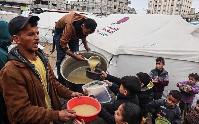 Des bénévoles distribuent des rations de soupe de lentilles corail à des Palestiniens déplacés à Rafah, dans le sud de la bande de Gaza, le 18 février 2024 (Crédit : SAID Khatib/AFP) Des bénévoles distribuent des rations de soupe de lentilles corail à des Palestiniens déplacés à Rafah, dans le sud de la bande de Gaza, le 18 février 2024 (Crédit : SAID Khatib/AFP)
