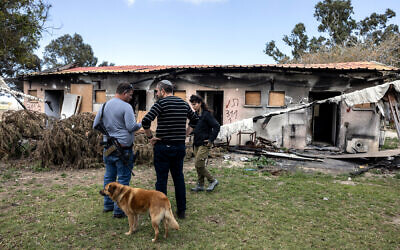 Des Israéliens devant une maison endommagée du kibboutz Nirim, à la frontière de la bande de Gaza, le 14 février 2024. (Crédit : Menahem Kahana / AFP)
