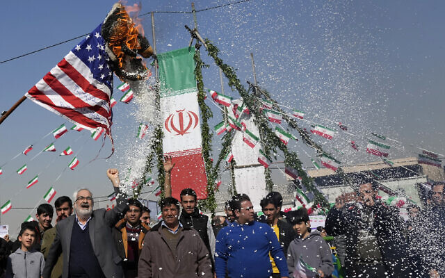 Des manifestants brûlant un drapeau américain durant un rassemblement annuel commémorant la révolution islamique de 1979, à Téhéran, en Iran, le 11 février 2024. (Crédit : Vahid Salemi/AP)