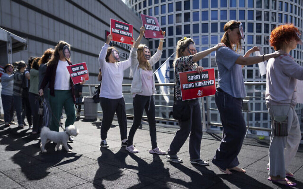 Des militants portent des masques représentant des Israéliens retenus en otage dans la bande de Gaza lors d'une manifestation à Tel Aviv, en Israël, le 21 février 2024. (Crédit : AP/Oded Balilty)