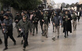 Illustration : Des hommes armés marchent devant les dépouilles de Said Jaradat et de Yasser Hanoun, toutes les deux enveloppées dans le drapeau du Jihad islamique palestinien, le 23 février 2024. (Crédit : AP Photo/Majdi Mohammed)