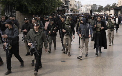 Illustration : Des hommes armés marchent devant les dépouilles de Said Jaradat et de Yasser Hanoun, toutes les deux enveloppées dans le drapeau du Jihad islamique palestinien, le 23 février 2024. (Crédit : AP Photo/Majdi Mohammed)