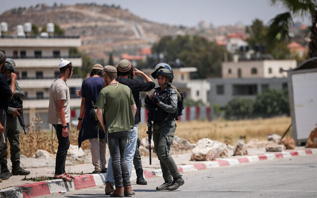 Illustration : Des soldats israéliens et des résidents d’implantations à l'entrée du village de Turmus Ayya, en Cisjordanie, 21 juin 2023. (Crédit : Yonatan Sindel/FLASH90) Illustration : Des soldats israéliens et des résidents d’implantations à l'entrée du village de Turmus Ayya, en Cisjordanie, 21 juin 2023. (Crédit : Yonatan Sindel/FLASH90)