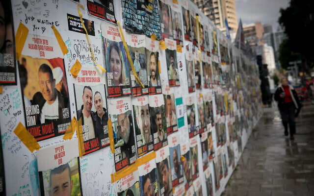 Des personnes passant devant des photos de civils pris en otage par les terroristes du Hamas à Gaza, sur la "Place des Otages", à Tel Aviv, le 14 février 2024. (Crédit : Miriam Alster/FLASH90)