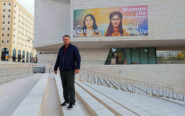 L'artiste irano-américain Hooman Khalili devant une peinture murale qu'il a réalisée sur le mur extérieur du Musée de la Tolérance de Jérusalem représentant la soldate irano-israélienne Shirel Pour Haïm (à gauche), et Mahsa Amini, jeune femme tuée par le régime, déclenchant des manifestations en Iran, à Jérusalem, le 30 janvier 2024. (Crédit : Gianluca Pacchiani/Times of Israel)