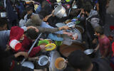 Des Palestiniens déplacés collectent de la nourriture donnée par une organisation caritative avant un repas d'iftar, le premier jour du mois de jeûne musulman du Ramadan, dans la ville de Rafah, dans le sud de Gaza, le 11 mars 2024. (Crédit : AFP)