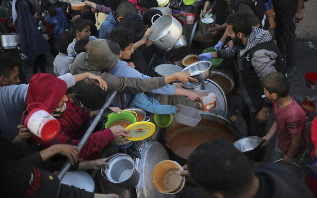 Des Palestiniens déplacés collectent de la nourriture donnée par une organisation caritative avant un repas d'iftar, le premier jour du mois de jeûne musulman du Ramadan, dans la ville de Rafah, dans le sud de Gaza, le 11 mars 2024. (Crédit : AFP) Des Palestiniens déplacés collectent de la nourriture donnée par une organisation caritative avant un repas d'iftar, le premier jour du mois de jeûne musulman du Ramadan, dans la ville de Rafah, dans le sud de Gaza, le 11 mars 2024. (Crédit : AFP)