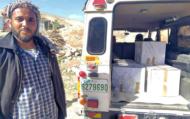 Un membre de la tribu Jahalin reçoit une aide alimentaire de la part d'activistes israéliens au début de l'année 2024, dans le désert de Judée. (Crédit : Rabbis for Human Rights)