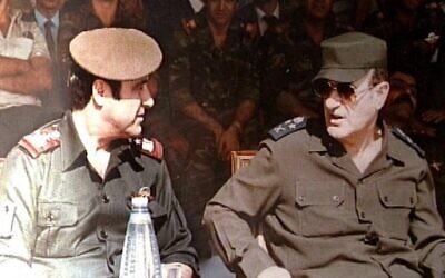 Le défunt président syrien Hafez al-Assad (à droite) avec son plus jeune frère Rifaat (à gauche) lors d'une cérémonie militaire à Damas, le 1er janvier 1984. (Crédit : AFP)