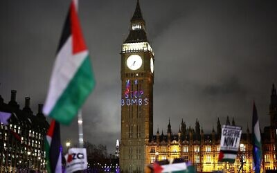 Un drapeau palestinien flottant à côté d'un message "Arretez les bombes" projeté sur la Tour Elizabeth, au Palais de Westminster, à Londres, le 21 février 2024. (Crédit : Henry Nicholls/AFP)