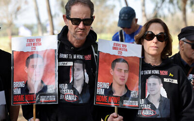 Ronen et Orna Neutra tenant des portraits de leur fils Omer Neutra, 22 ans, alors que des parents et des sympathisants des otages israéliens détenus à Gaza depuis les attaques du 7 octobre par les terroristes du Hamas, se rassemblent avant le début d'une marche de quatre jours vers Jérusalem appelant à leur libération, sur le site du Festival Supernova, à proximité du kibboutz Reïm, dans le sud d'Israël, le 28 février 2024. (Crédit : Jack Guez/AFP)