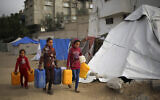 Des fillettes palestiniennes transportant des bidons d'eau dans une rue de Rafah, dans le sud de la bande de Gaza, le 3 mars 2024. (Crédit : AFP)