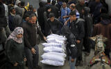 Un Palestinien transportant des sacs d'aide humanitaire au centre de distribution de l'UNRWA à Rafah, dans le sud de la bande de Gaza, le 3 mars 2024. (Crédit : AFP)
