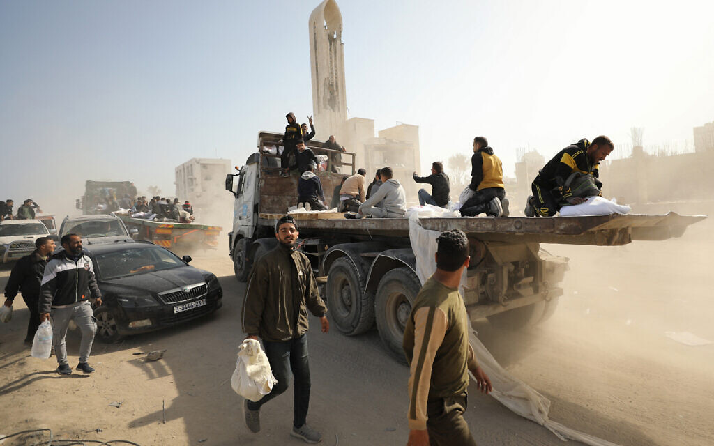 Des Palestiniens transportent des sacs de farine à l'arrière de camions alors que l'aide humanitaire arrive dans la ville de Gaza le 6 mars 2024. (Crédit :  AFP)