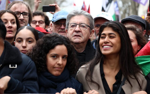 Jean-Luc Mélenchon (au centre), leader de La France Insoumise (LFI), Rima Hassan (à droite), fondatrice franco-palestinienne de l'Observatoire des camps de réfugiés (OCR) et tête de liste de LFI pour les élections européennes, et Manon Aubry (à gauche) brandissent une banderole lors d'une manifestation appelant à un cessez-le-feu à Gaza, place de la République, à Paris, le 9 mars 2024. (Crédit : Emmanuel Dunand/AFP)