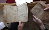 Des membres du Centre du Kurdistan pour les arts et la culture (KCAC) inspecte de vieux livres avant de les numériser dans le cadre d'un effort visant à préserver les volumes et manuscrits historiques de la communauté, à Dohouk, dans le nord de l'Irak, le 13 février 2014. (Crédit : Safin Hamid/AFP)