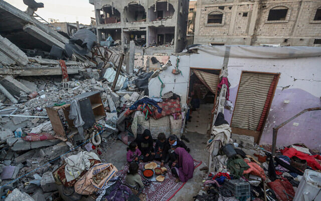 Des membres de la famille Rabaya rompant le jeûne au milieu des décombres de leur maison, qui a été détruite par une frappe israélienne, pendant le ramadan à Rafah le 23 mars 2024. (Crédit : Said Khatib/AFP)