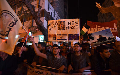 Un Tunisien brandit une pancarte où l'on peut lire qu'Israël est "le nouveau nazisme" lors manifestation de solidarité avec le peuple palestinien, à Tunis, le 30 mars 2024. L'étoile de David du drapeau de l'État juif a été remplacée par une croix gammée.
(Crédit : FETHI BELAID / AFP)