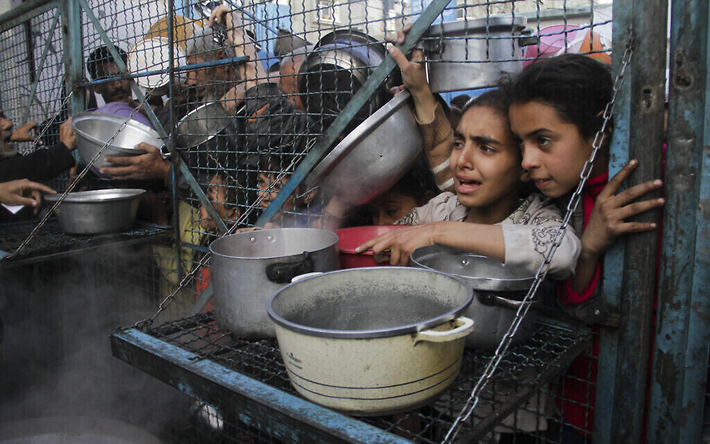 Des enfants palestiniens font la queue pour recevoir des repas gratuits au camp de réfugiés de Jabaliya, dans la bande de Gaza, le 18 mars 2024. (Crédit : AP Photo/Mahmoud Essa)